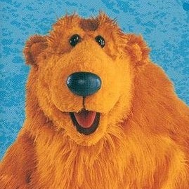 A bright orange bear puppet with a dark blue nose and beady little black eyes.