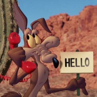A brown cartoon coyote with a long, pale tan snout. He is holding a telephone in one hand, and a sign in his other.