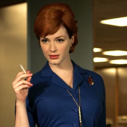 A square picture of Joan Harris from Mad Men as portrayed by Christina Hendricks. She is a pale, ginger woman wearing a deep blue dress and holding a cigarette.